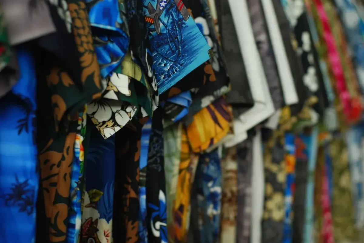 Deretan kemeja aloha bermotif bunga dan pemandangan tropis warna biru, cokelat, kuning, dan merah muda yang digantung berjajar di Papeete, Polinesia Prancis.
