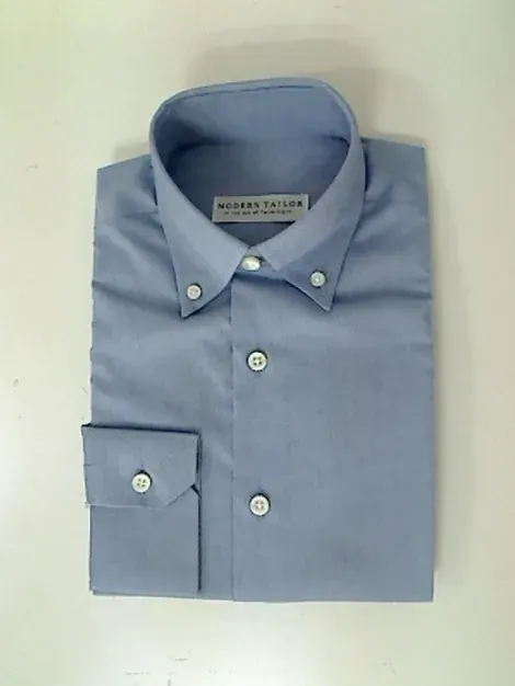 Kemeja oxford biru muda terlipat rapi dengan kerah button-down, ujung kerah dikancingkan ke badan kemeja dan manset berkancing satu.